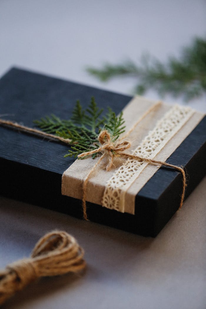 category-01 Black gift box wrapped with twine and lace, accented with a green leaf.
